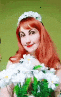 a woman with red hair is wearing a flower crown and holding a bouquet of white flowers