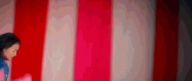 a woman is standing in front of a red and white striped curtain .