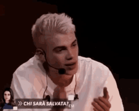a man wearing a microphone and a white shirt is talking to a woman .