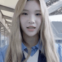 a woman with long blonde hair is wearing a blue and white shirt and a blue vest .