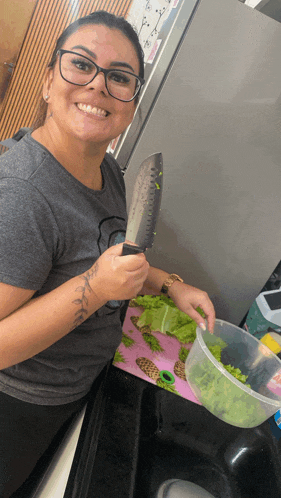 a woman with glasses is smiling while holding a knife