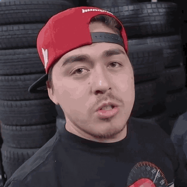 a man wearing a red hat and a black shirt has a speedometer on his shirt