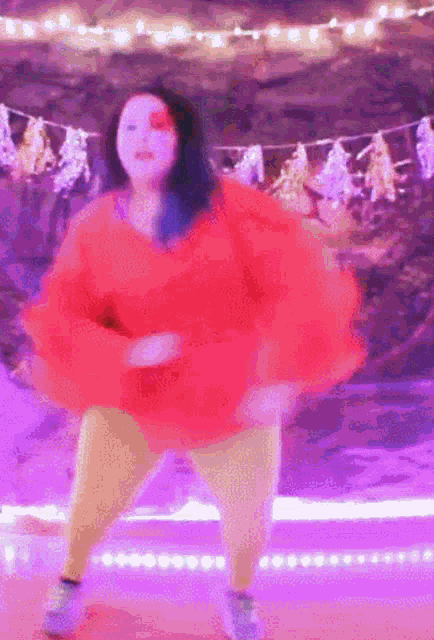 a woman in a red top and yellow pants is dancing on a stage .