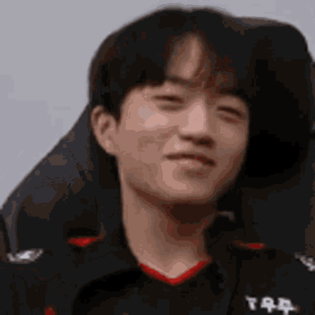 a close up of a young man sitting in a chair making a funny face .