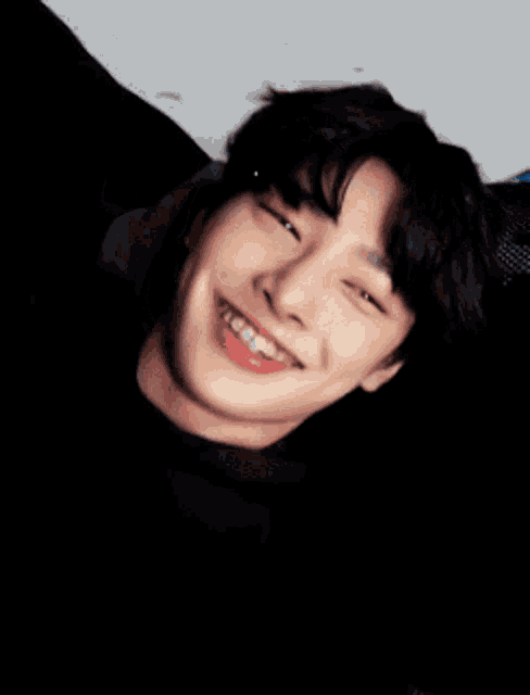 a young man with braces on his teeth is smiling with his eyes closed .