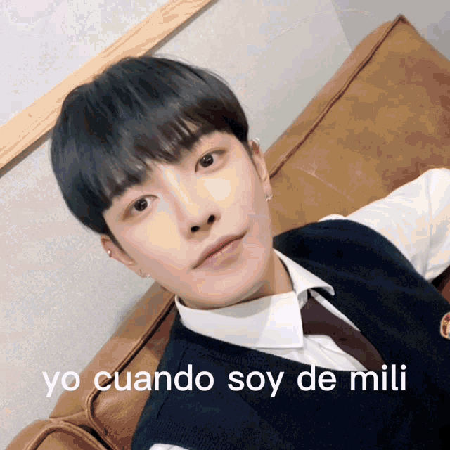 a young man is sitting on a couch with the words yo cuando soy de mili written below him