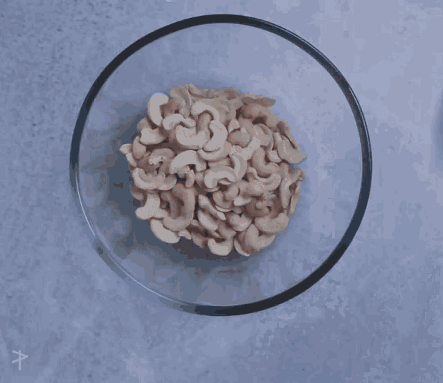 a person 's hand is reaching into a bowl filled with cashews