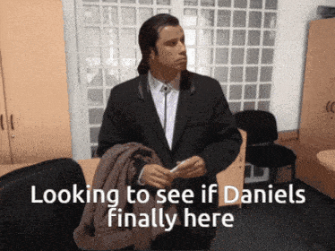 a man in a suit is standing in an office with the words looking to see if daniels finally here below him