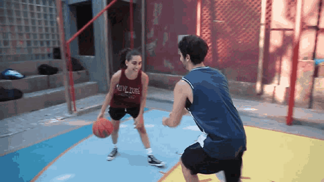 a man and a woman are playing basketball and the woman is wearing a shirt that says new york