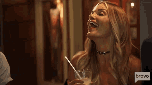 a woman is laughing while holding a drink with a straw in her mouth .