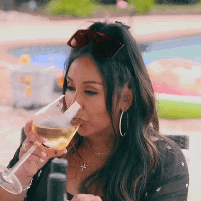 a woman wearing sunglasses is drinking from a glass
