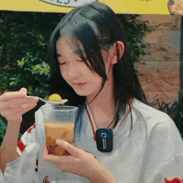 a girl with long hair is holding a cup and a spoon in her hand .