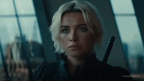 a close up of a woman with blonde hair holding a sword .