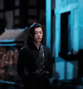 a man in a black kimono stands in front of a building