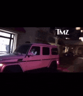 a woman is sitting in a pink car that says tmz on the bottom