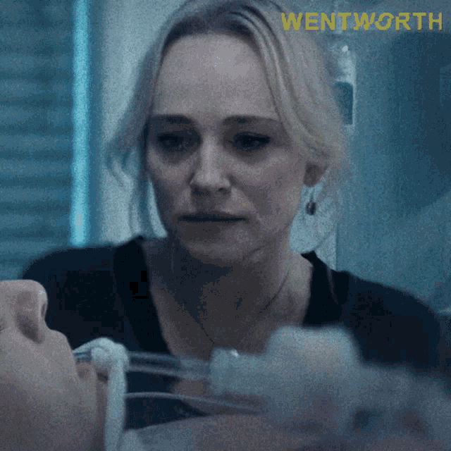 a woman is looking at a man laying in a hospital bed with wentworth written on the bottom