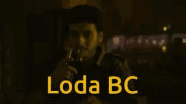 a man is drinking a glass of wine in a dark room with the words loda bc .