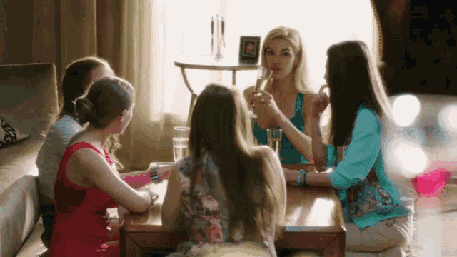 a group of women sit around a table drinking champagne