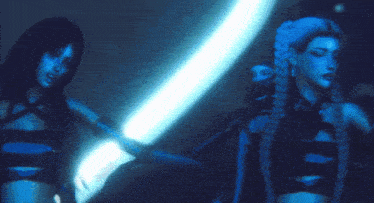 two women are standing next to each other in a dark room with blue lights behind them