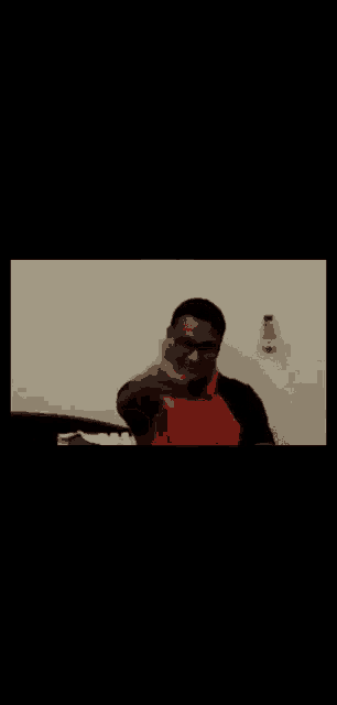 a man wearing glasses and an orange shirt is waving his hand .