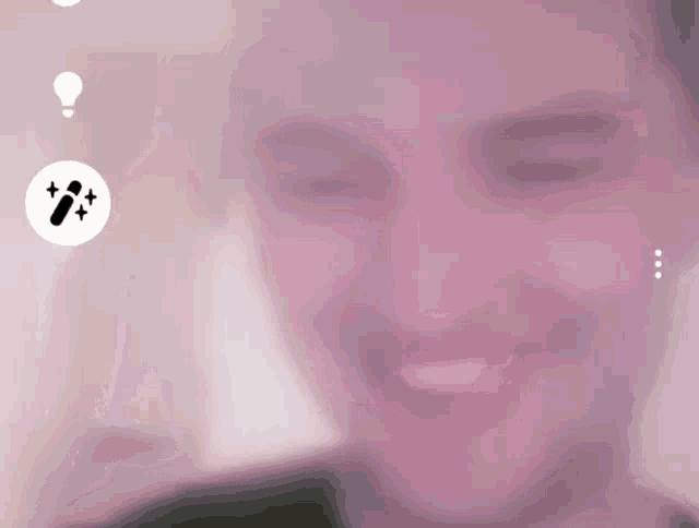 a blurry picture of a man 's face with a light bulb and a pencil icon in the corner