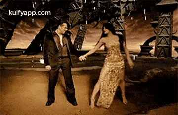 a man in a suit and a woman in a long dress are holding hands and dancing in the rain .