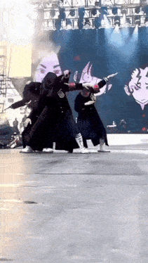 a group of people are dancing on a stage with a large screen behind them .
