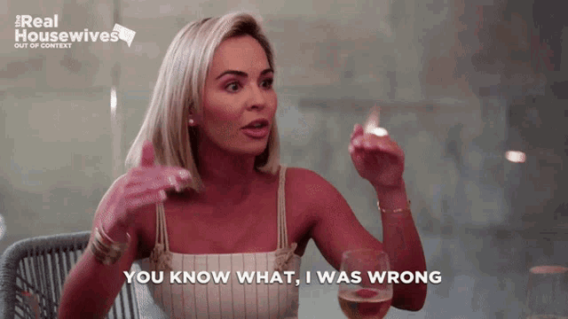 a woman is sitting at a table with a glass of wine and says " you know what i was wrong "
