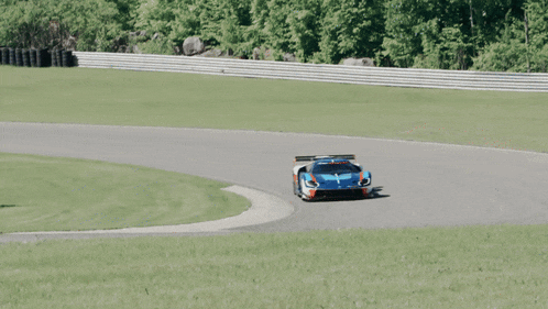 a blue race car is driving down a road