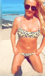 a woman in a leopard print bikini and sunglasses is kneeling on the beach