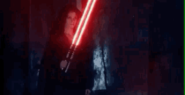 a person is holding a red lightsaber in their hand in a dark room .