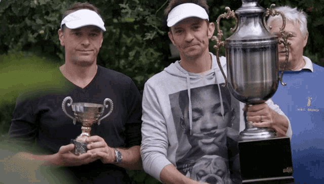 two men holding trophies with one wearing a shirt that says ' walt disney ' on it