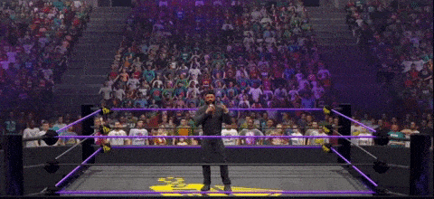 a man stands in a wrestling ring with a microphone in his hand