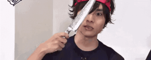 a man is holding a knife in front of his face and making a funny face .