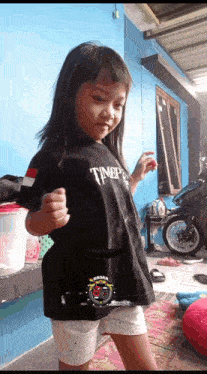 a little girl is wearing a black t-shirt that says tnbp