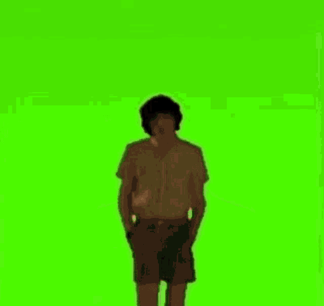 a man in a striped shirt is standing on a green screen .