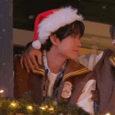 a man wearing a santa hat is hugging another man