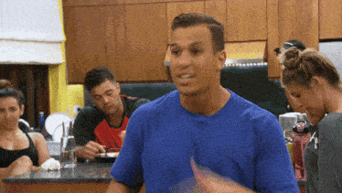 a man in a blue shirt is standing in front of a group of people