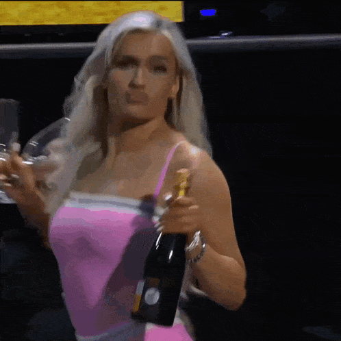 a woman in a pink dress is holding a bottle of champagne and a glass