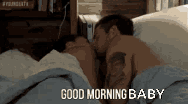 a man and a woman are laying in bed kissing .