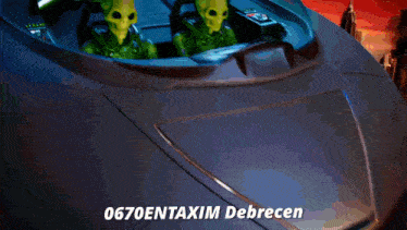 two green aliens are sitting in the cockpit of a vehicle with the words 0670entaxim debrecen written on the bottom