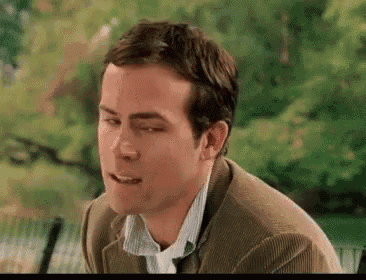 a man in a suit and tie is sitting on a bench with his eyes closed and his mouth open .