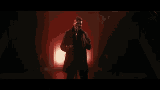 a man is singing into a microphone in a dark room with red lights .