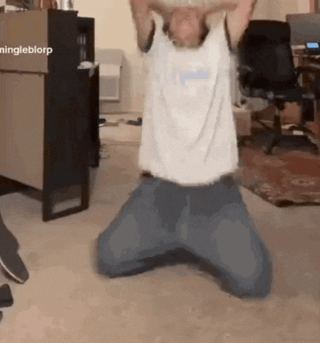 a man is kneeling on the floor in a living room with his arms outstretched .