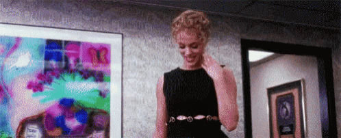 a woman in a black dress is standing in a room in front of a framed picture .