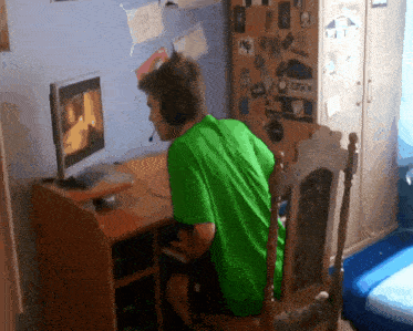 a man in a green shirt is sitting in front of a computer