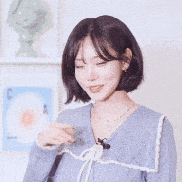 a woman wearing a blue sweater and a necklace with a microphone on her neck