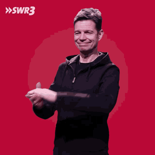 a man is dancing in front of a red background with swr3 written in white