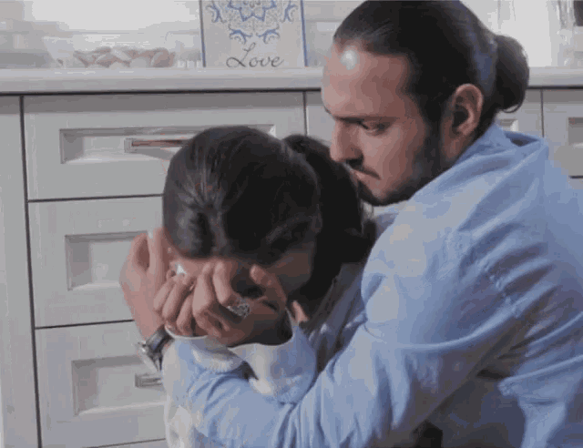 a man in a blue shirt is hugging a woman in front of a blue box that says love