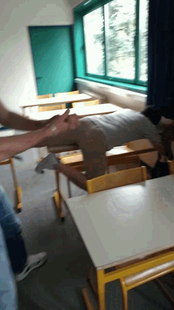 a person is laying on a desk in a classroom with a green door